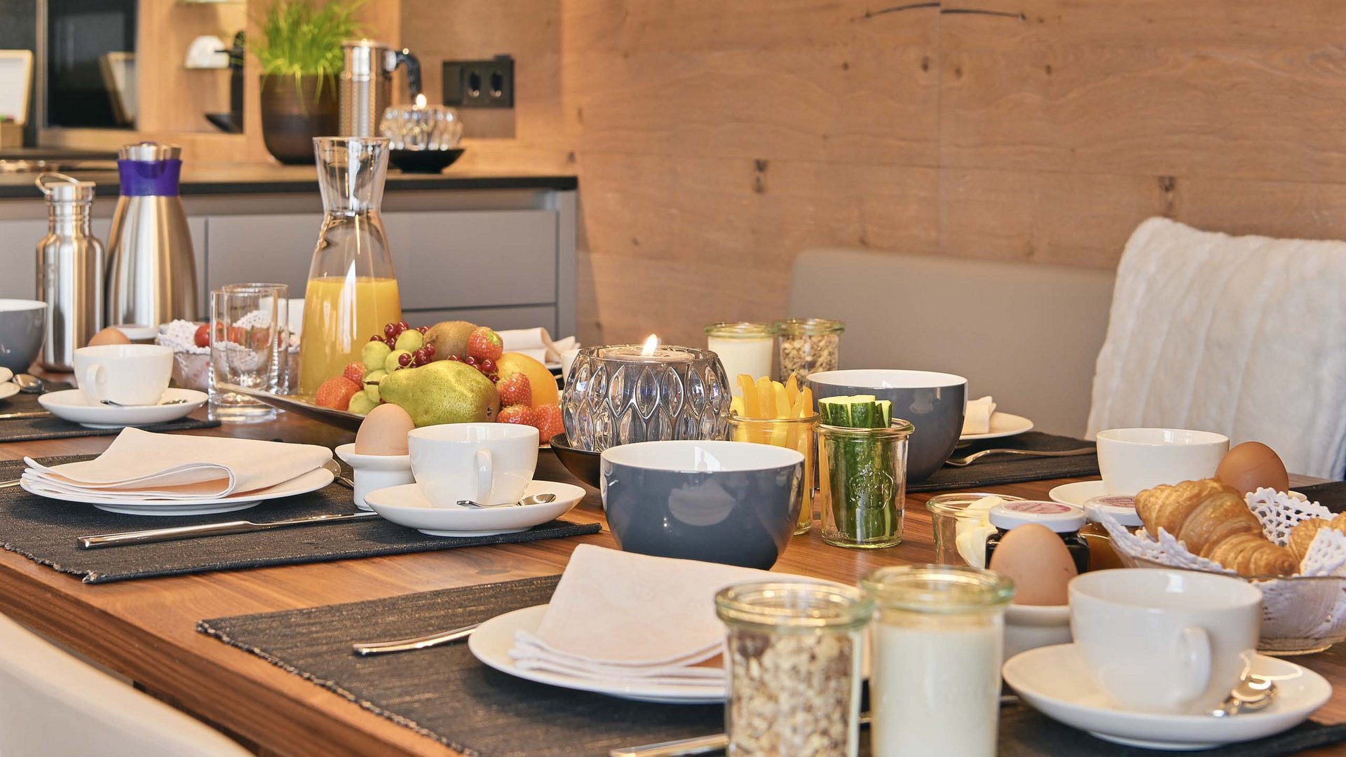 Frühstückstisch mit Tassen, Obst, Croissants und Eiern in modernem Esszimmer