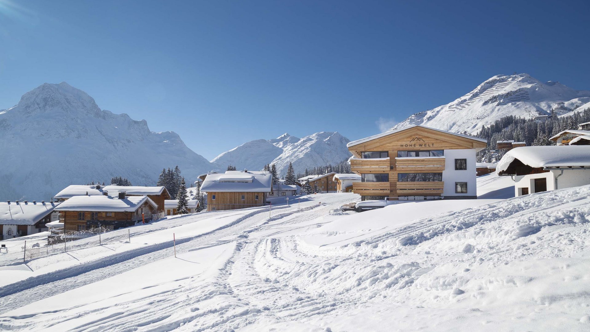 Winterliches Bergdorf mit schneebedeckten Häusern unter klarem blauen Himmel