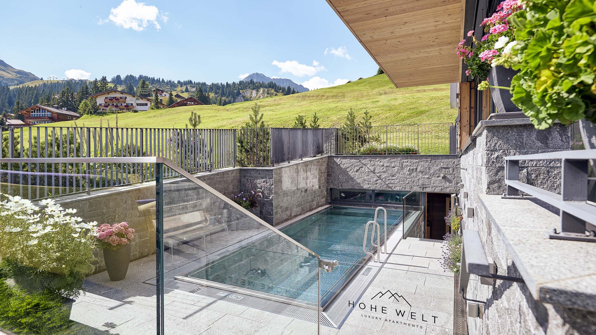 Moderner Poolbereich mit Bergblick und Blumen an einem Luxusapartment